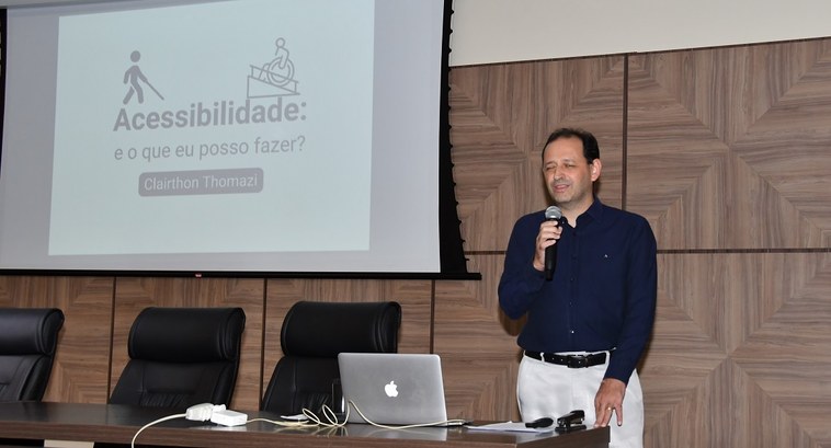 Servidor Clairton Thomazi falando com o painel do slide ao fundo dizendo "Acessibilidade: e o qu...