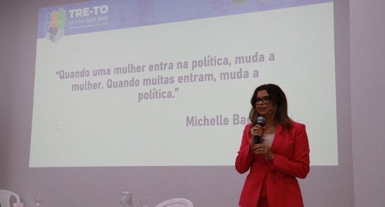 Juíza Edssandra Barbosa palestrando, com o slide atrás dizendo "Quando uma mulher entra na polít...